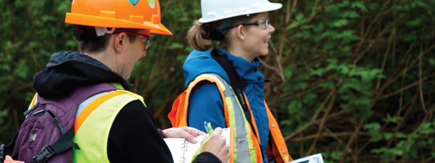 Two women in hard hats take notes