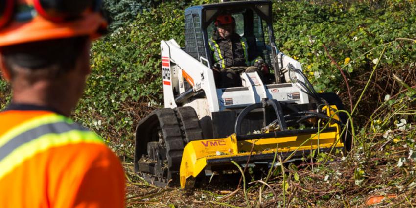 Out of focus person in foreground watches a machine clear brush