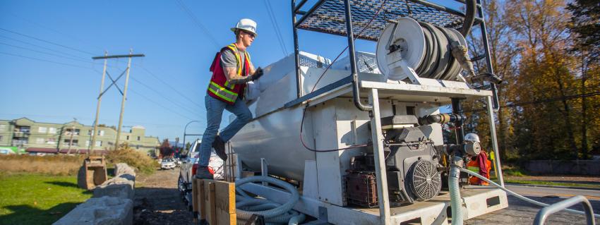 Man stands on the edge of a hydroseed machine