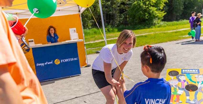 FortisBC team member hands boy a balloon at the Great Salmon Send-off