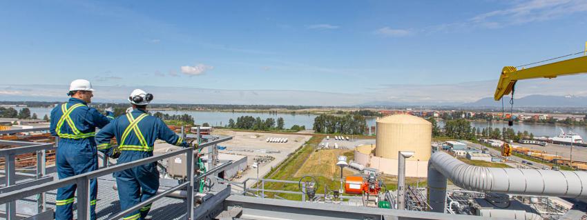 Two men stand on a platform overlooking the Tilbury LNG facility