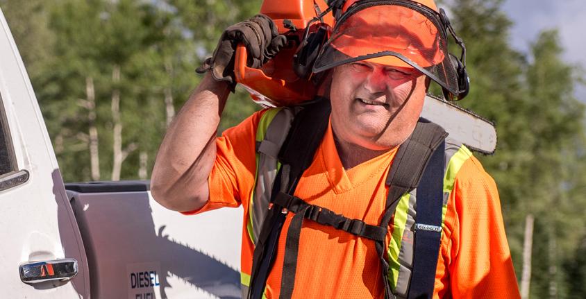 Man holds a chainsaw over his shoulder