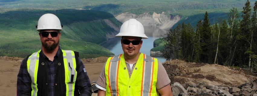 Two men wearing safety gear pose for the camera, on an Inland Gas Upgrade worksite near Mackenzie