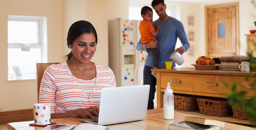 woman works on a computer at her kitchen table