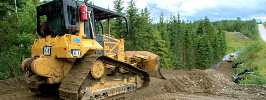 Bulldozer sits on a hill along a clearing