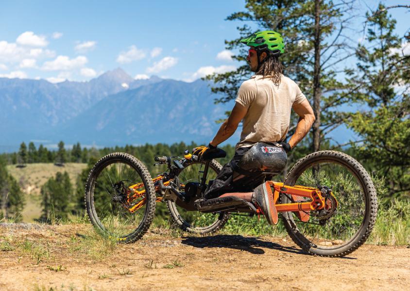 Man sits on an adaptive mountain bike looking out over forest