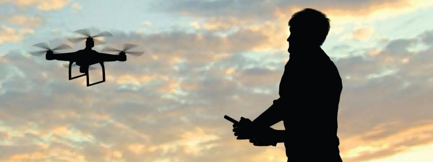 Backlit man flies a drone