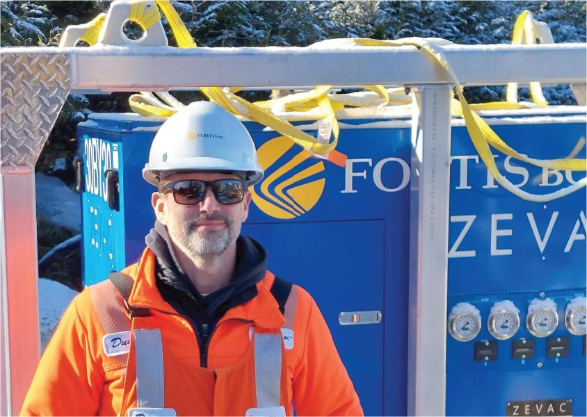 Duane Mrak stands in front of a ZEVAC machine