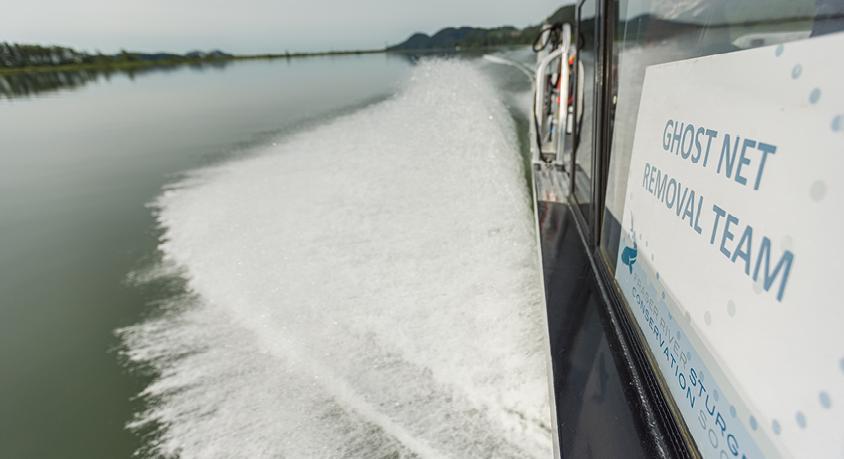 Ghost net removal team boat leaves a wake in the river