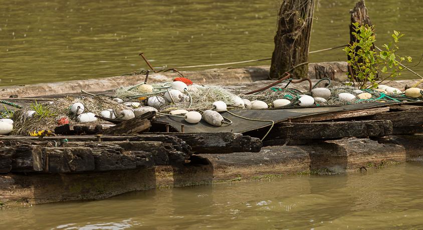 Ghost gear nets sit on a dock along the river